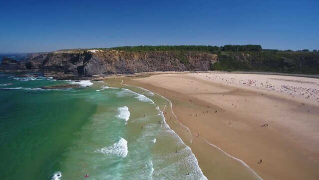 Aerial video filming by drone of the sea bay and beach near the village of Odeceixe Alentejo Portugal. Tourists sunbathe on the beach.