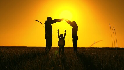 Happy family, mother, father, daughter, child, dream of building house, housing for family. Teamwork silhouette. Family shows house with their own hands, symbol of happiness, comfort for child, sunset