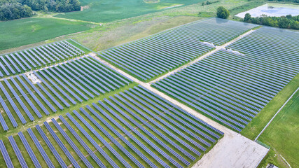 Aerial over solar farm Solar panels facing straight up with swamp and farmland around it
