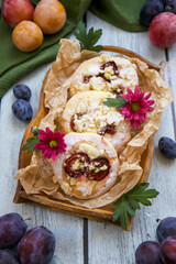 Delicious and sweet bun with plums on a rustic wooden tray