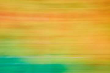 Abstract streaks of pastel orange and yellow blurred with green on bottom