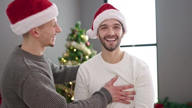 Two men couple celebrating christmas hugging each other kissing at home