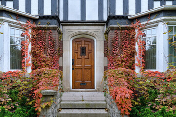 Front door of old Tudor style house surrounded by ivy