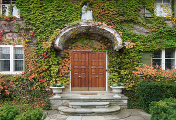 Front of old ivy covered house with elegant wood grain double doors