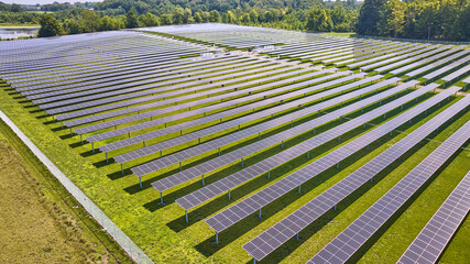 Green grass around rows of solar panels on farm in Midwest aerial
