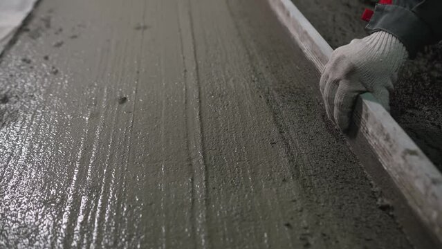 A builder uses a trowel to level a cement mortar screed. Concrete work on a construction site. Installation work using trowels. Leveling fresh mortar using a tool.