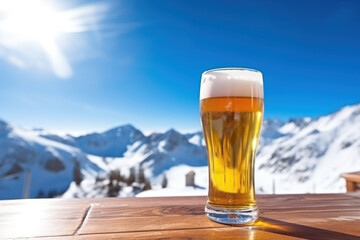 A glass of fresh foamy light beer on the table of a ski resort cafe on a sunny day - obrazy, fototapety, plakaty