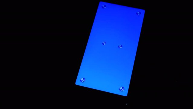 Smartphone with a Blue Screen Rotates on a Black Background in the Dark Room. Empty space, a place for text. Markers. Gadget, a mobile phone with a glowing screen. Chrome kay background. Close up.