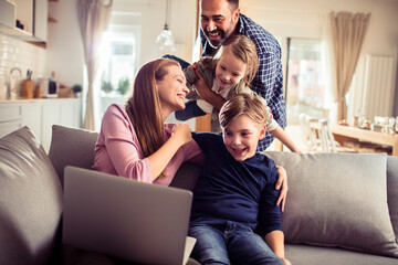 Happy young family spending time together with a laptop in the living room