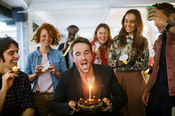 Young businessman celebrating his birthday with colleagues in a modern office