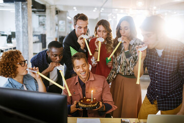 Young businessman celebrating his birthday with colleagues in a modern office