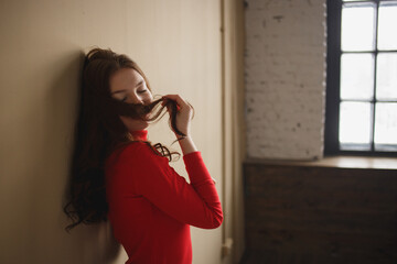 Close up young attractive woman 20s in red turtleneck isolated on plain pastel beige background...