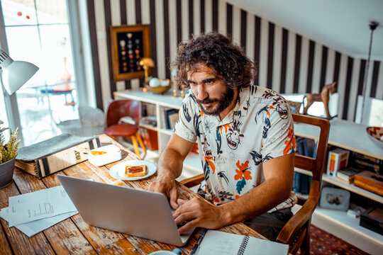 Focused young man paying bills online at home
