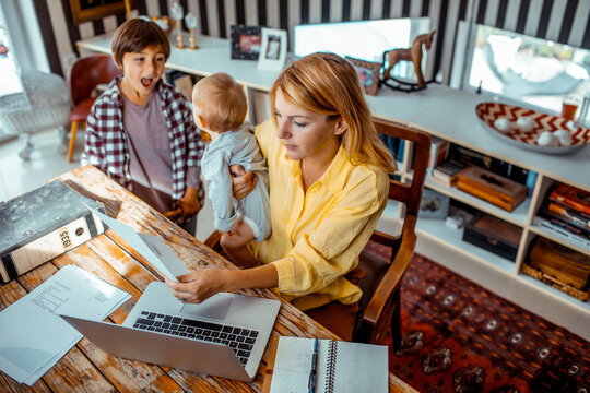 Working mom doing financials and watching her children at home