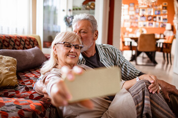 Loving elderly couple taking a selfie at home