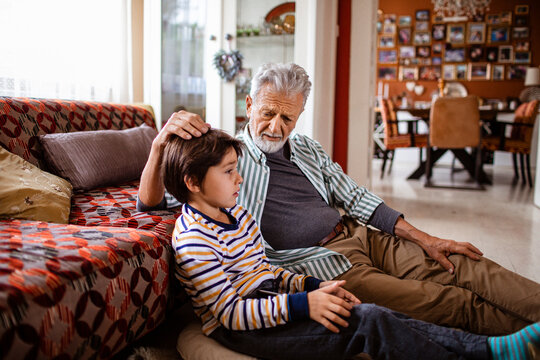 Concerned grandfather comforting his grandson at home after a bullying accident at school