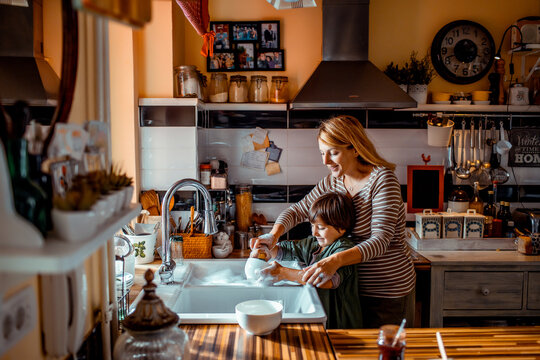 Caring young boy helping his mother with the dishes in the kitchen