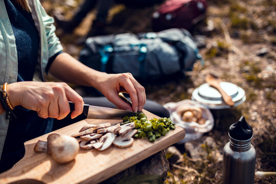 Close up of a woman cutting vegetables while out camping in the woods
