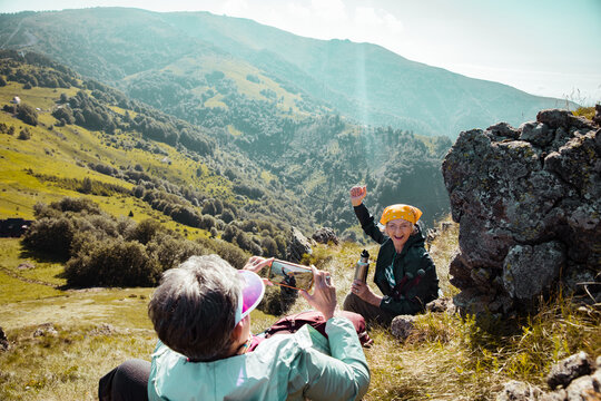 Cheerful elderly woman getting her picture taken while hiking in the mountains
