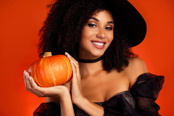 Close up photo of powerful charming witch showing pumpkin decor for collect sweets trick or treat over red background