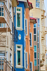 Side view of colorful housing with jutting out windows in a long row of buildings