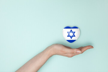 Heart with print of Israel flag in female hands. Flat lay.