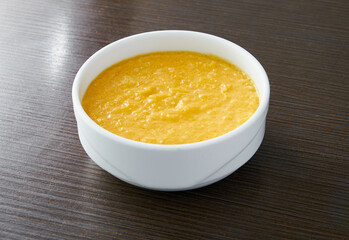 A bowl of pumpkin porridge on a textured dark brown table - an appetizing blend of Thanksgiving and healthy dining, embodying the essence of nourishing traditions.