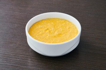A bowl of pumpkin porridge on a textured dark brown table - an appetizing blend of Thanksgiving and healthy dining, embodying the essence of nourishing traditions.