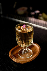 Old fashioned drinking glass with transparent cocktail decorated with dried orange, silver beads and little rose flower