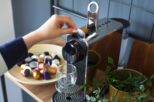 Hand inserting a capsule into a coffee machine at home. Concept of a coffee break.