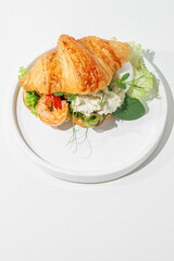 Bruschetta, croissant with shrimp and poached egg on a white table, sunny hard light.
