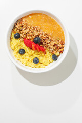 Millet porridge with blueberries and rolled oats on a white table , sunny hard light, healthy breakfast