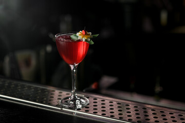 Sweet alcoholic cocktail in drinking glass decorated with green leaf and citric fruits isolated on dark background.