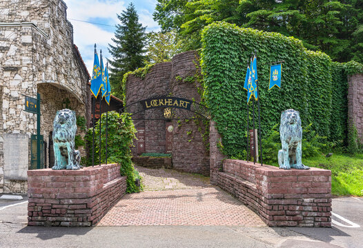 gunma, japan - jul 18 2023: Entrance gate of the Lockheart Castle adorned with two bronze statues of lions against the brick wall covered by grapevine of this European castle relocated from Edinburgh.