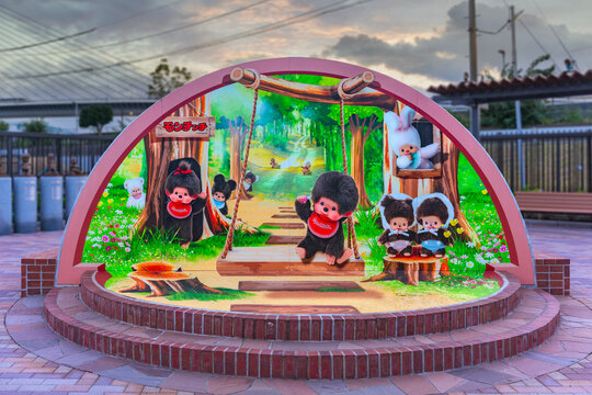 tokyo, japan - sep 12 2023: Monument photo spot in the Monchichi Parc at evening in Shinkoiwa depicting Japanese stuffed monkey toys called also kiki in a forest sitting on a swing and on tree trunks.