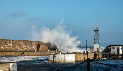 Storm Babet hitting a harbour wall with big waves over the wall in Scotland 