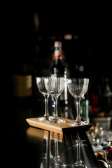 Empty clean glasses for alcoholic drinks in restaurant on bar counter with bottle on blurred background