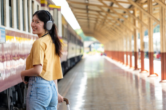 Cheerful young woman standing against train at tram station