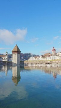 Scenic of Historic city center with famous Chapel Bridge and lake Lucerne on a morning cloudy day and blue sky, Canton of Lucerne, Switzerland. Tourist destination in autumn. Vertical mobile screen.