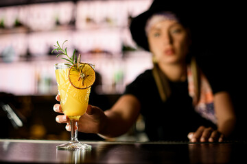 Selective focus on Blood orange paloma cocktail in woman's Bartender hand at bar counter
