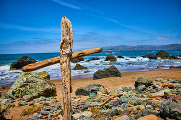Inspiration and motivation in religious cross on shore with ocean waves and blue and purple sky