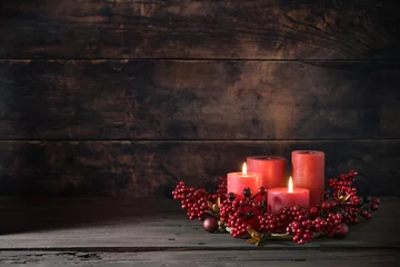 Foto op Canvas Second Advent with two lit red candles in a wreath from berries with Christmas decoration against a dark rustic wooden background, copy space, selected focus © Maren Winter