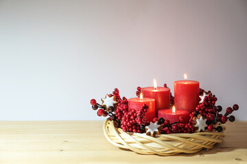 Fourth advent with four lit red candles in a natural willow wicker wreath with cinnamon star...