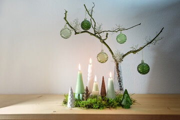Alternative advent wreath decoration with four different candles, small artificial Christmas trees...