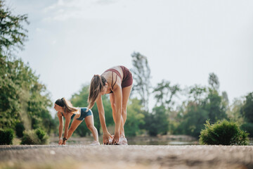 Fit Girls Training Outdoors: Inspiring Athletic Females Stretching and Warming up in a Green Park for Pre-Workout Fitness