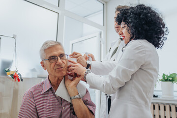 Fototapeta premium Healthcare professionals checking eyesight, hearing, and throat. Cleaning ears, examining elderly patient. Successful diagnosis, empathetic conversation in clinic.