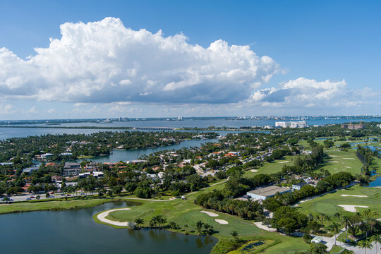 Aerial shot of a gorgeous summer landscape at Miami Beach Golf Club with lush green grass and trees, blue ocean water, homes and hotels in the skyline in Miami Beach Florida USA