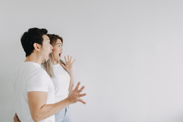 Surprised and shocked face of exciting asian couple lover looking at empty space