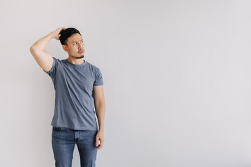 Confused face of asian man in blue t-shirt stand isolated on white.