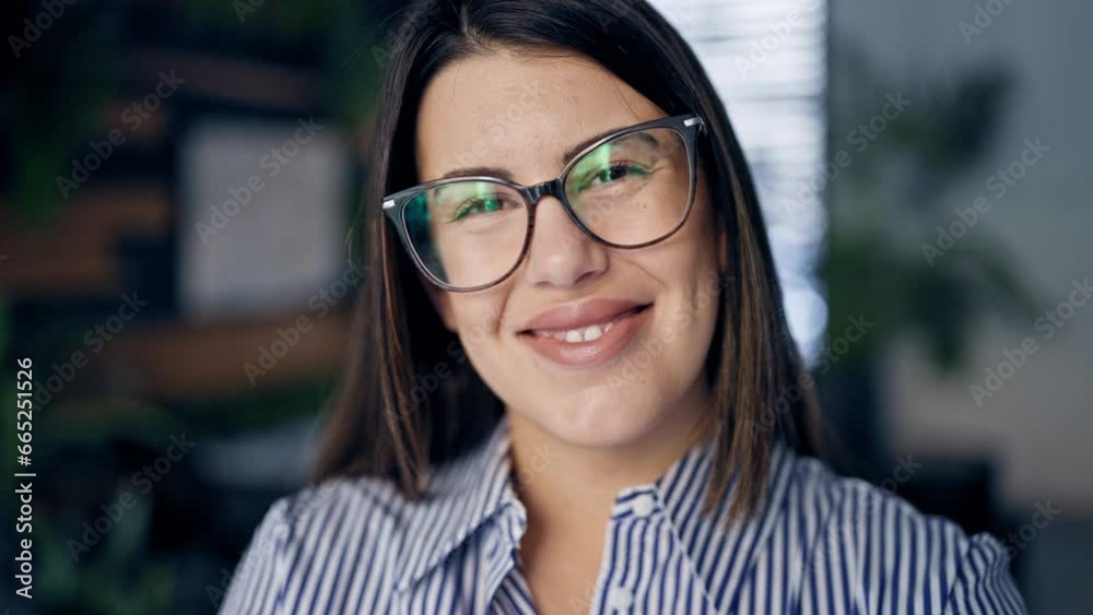 Wall mural Young beautiful hispanic woman wearing glasses smiling happy at the office